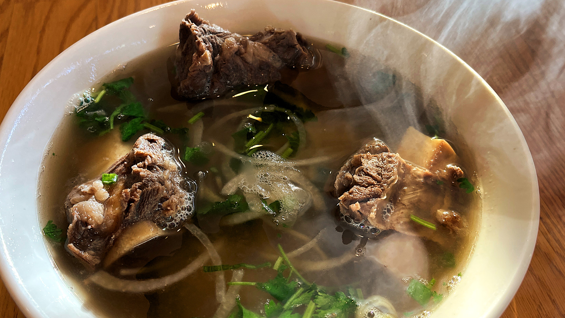 Vietnamese pho with beef short ribs, clear broth, rice noodles, and fresh herbs