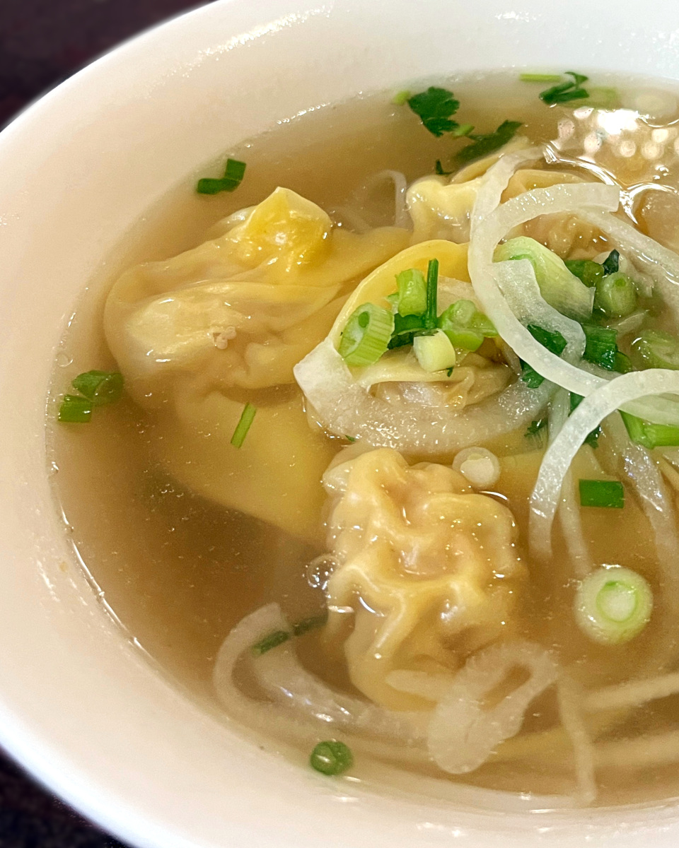 Smooth wontons are full of a bowl of beef broth.
