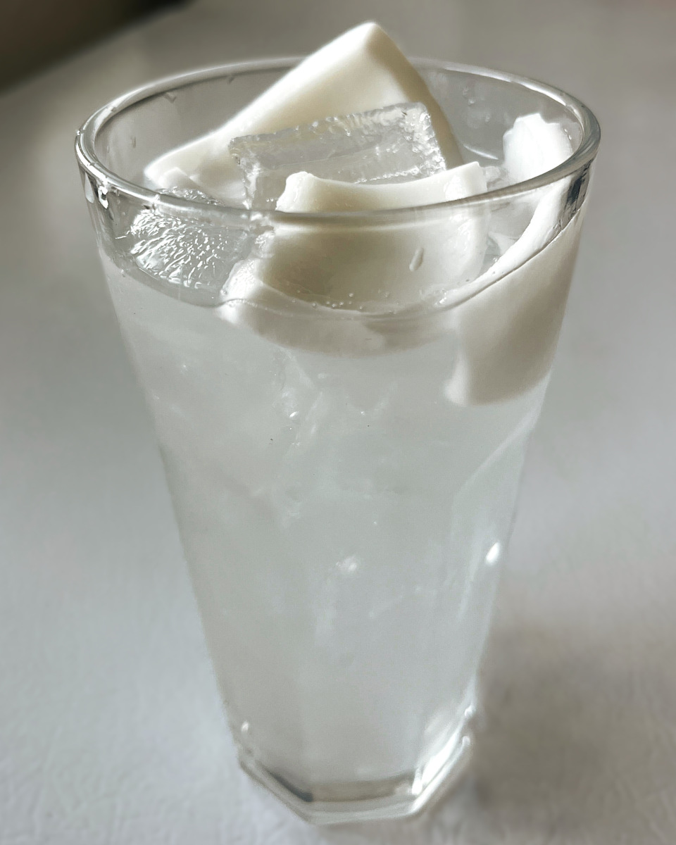 young coconut juice with coconut flesh in glass